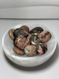 Rhodochrosite polished palmstones in white crystal bowl