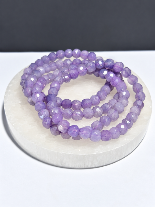 AA Lavender Moon Quartz 6mm faceted stretch bracelet on white stone display
