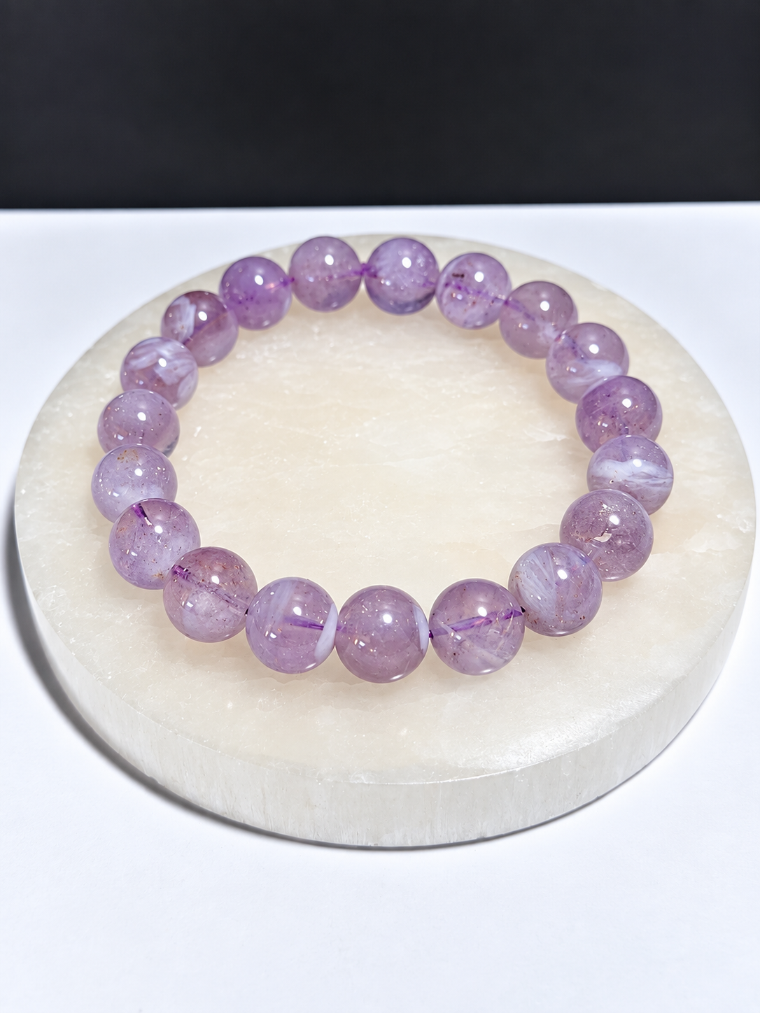 Certified Lavender Moon Quartz 10mm stretch bracelet on white stone display