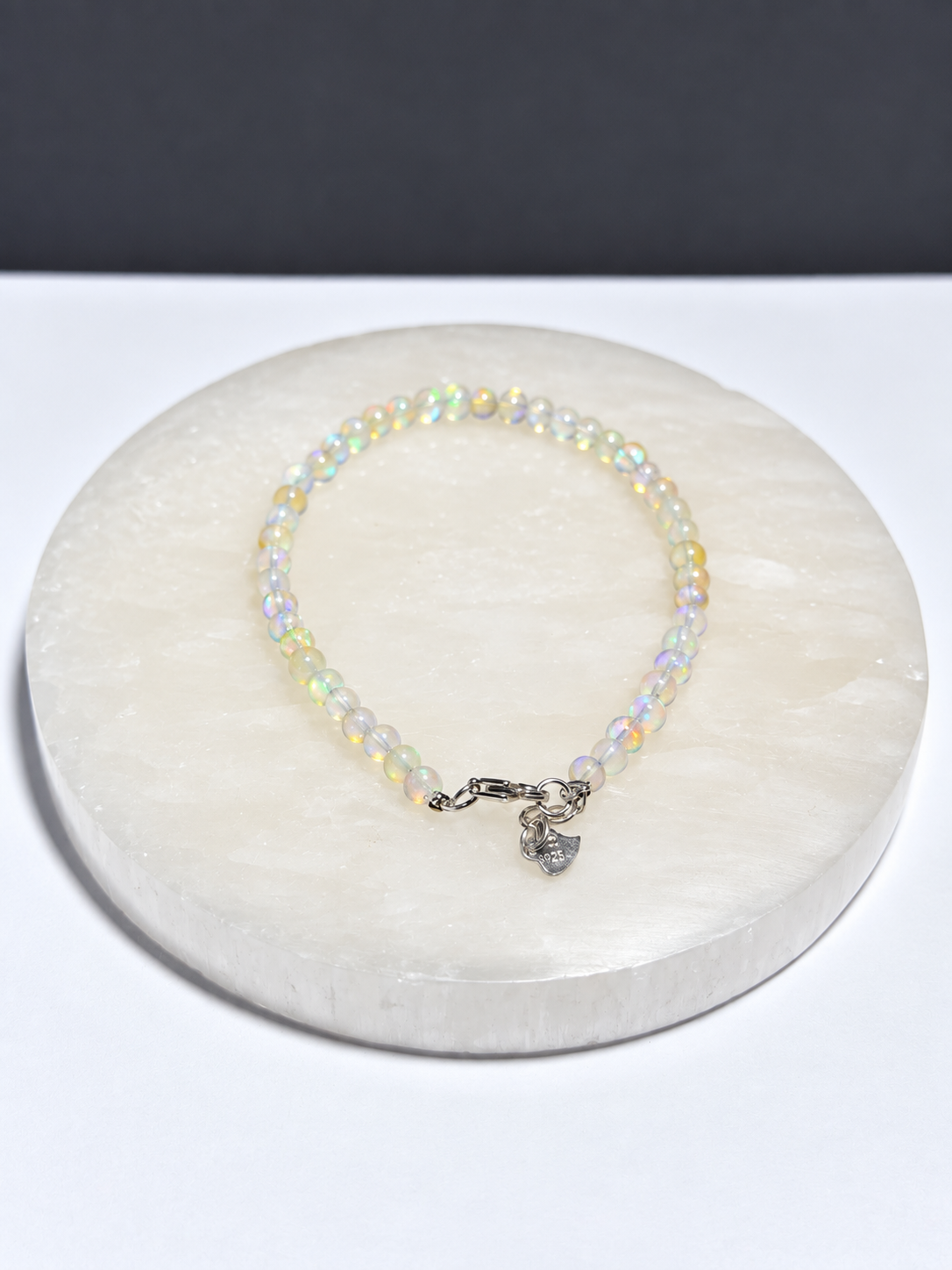 Ethiopian Opal 3mm adjustable bracelet with S925 clasp on white stone display