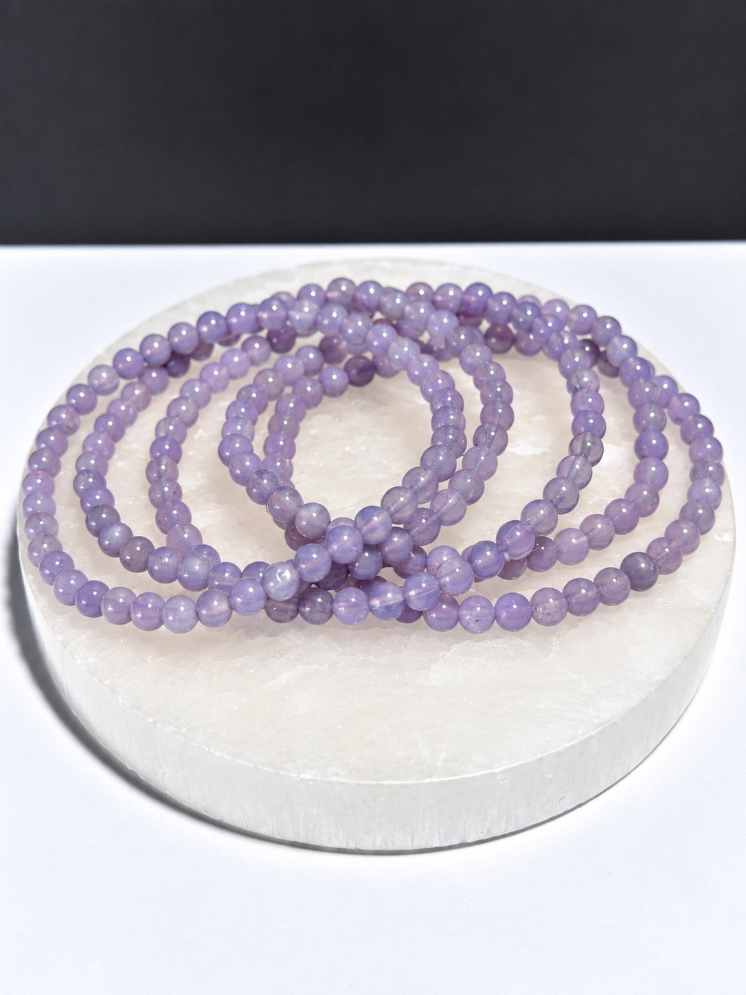 High-grade Lavender Moon Quartz 5mm round stretch bracelets on white stone display