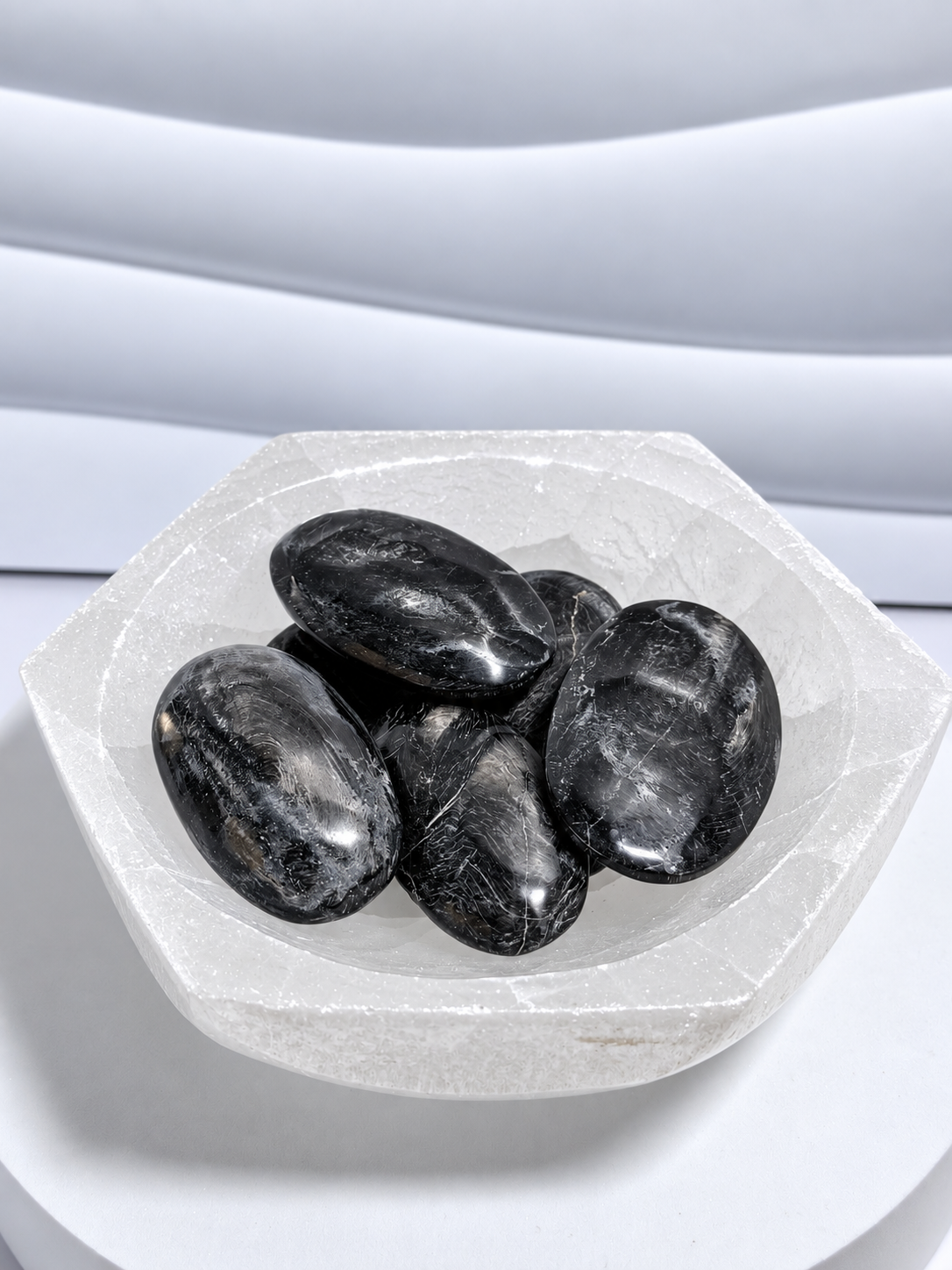 Five low-grade hypersthene palm stones approximately 2.5 to 3 inches long with rough finish and mild chatoyancy