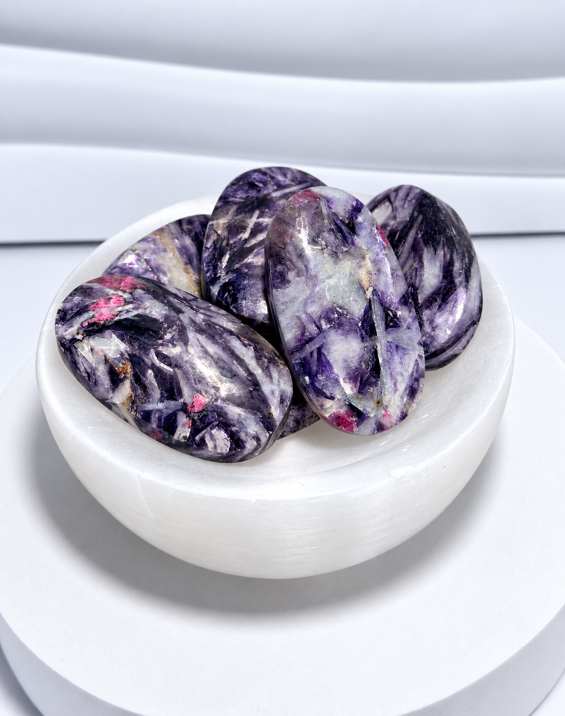 Mica with Pink Tourmaline palm stones in purple, lavender, gray and pink tones displayed in a white crystal bowl