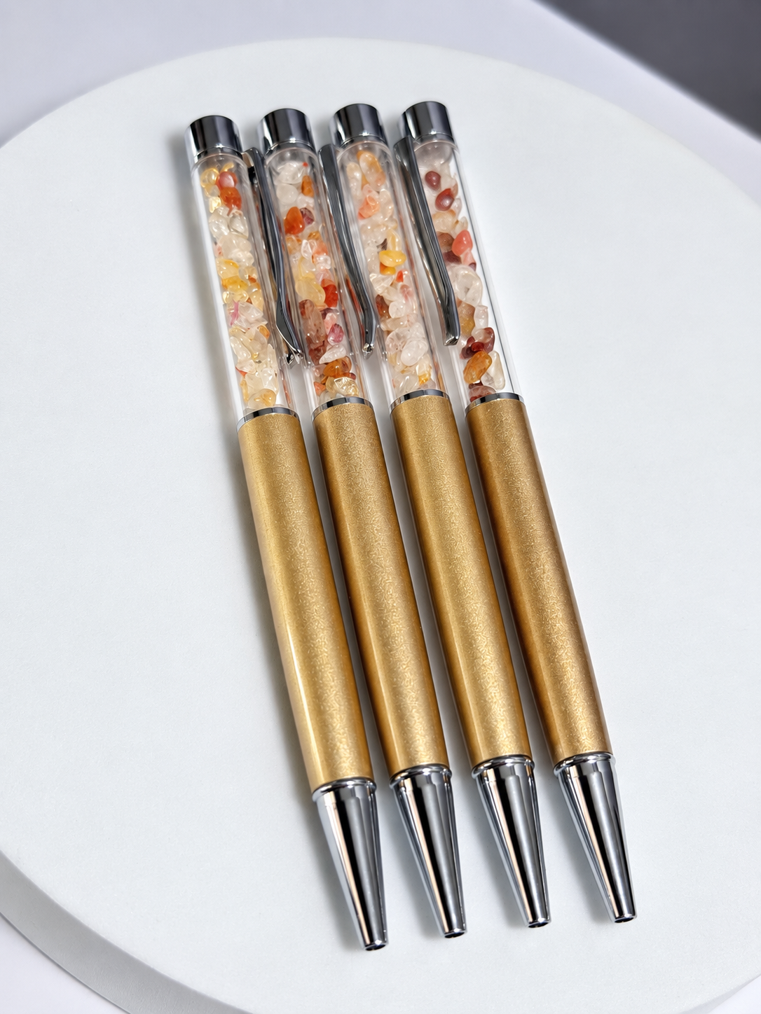 Gold pen with black ballpoint ink filled with fire quartz, clear quartz, and citrine chips