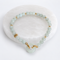 Pale green jade bracelet with 4mm beads, donut-style peace buckle focal bead, and brass embellishments