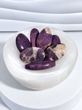 Phosphosiderite palm stones in rich purple tones with cream, gray, black, and earthy matrix patterns displayed in a white crystal bowl