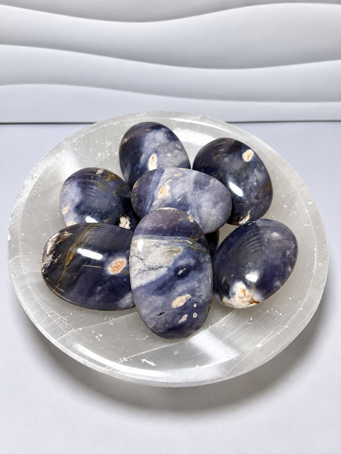Purple chalcedony palm stones in polished blue-violet tones with natural cream and tan inclusions