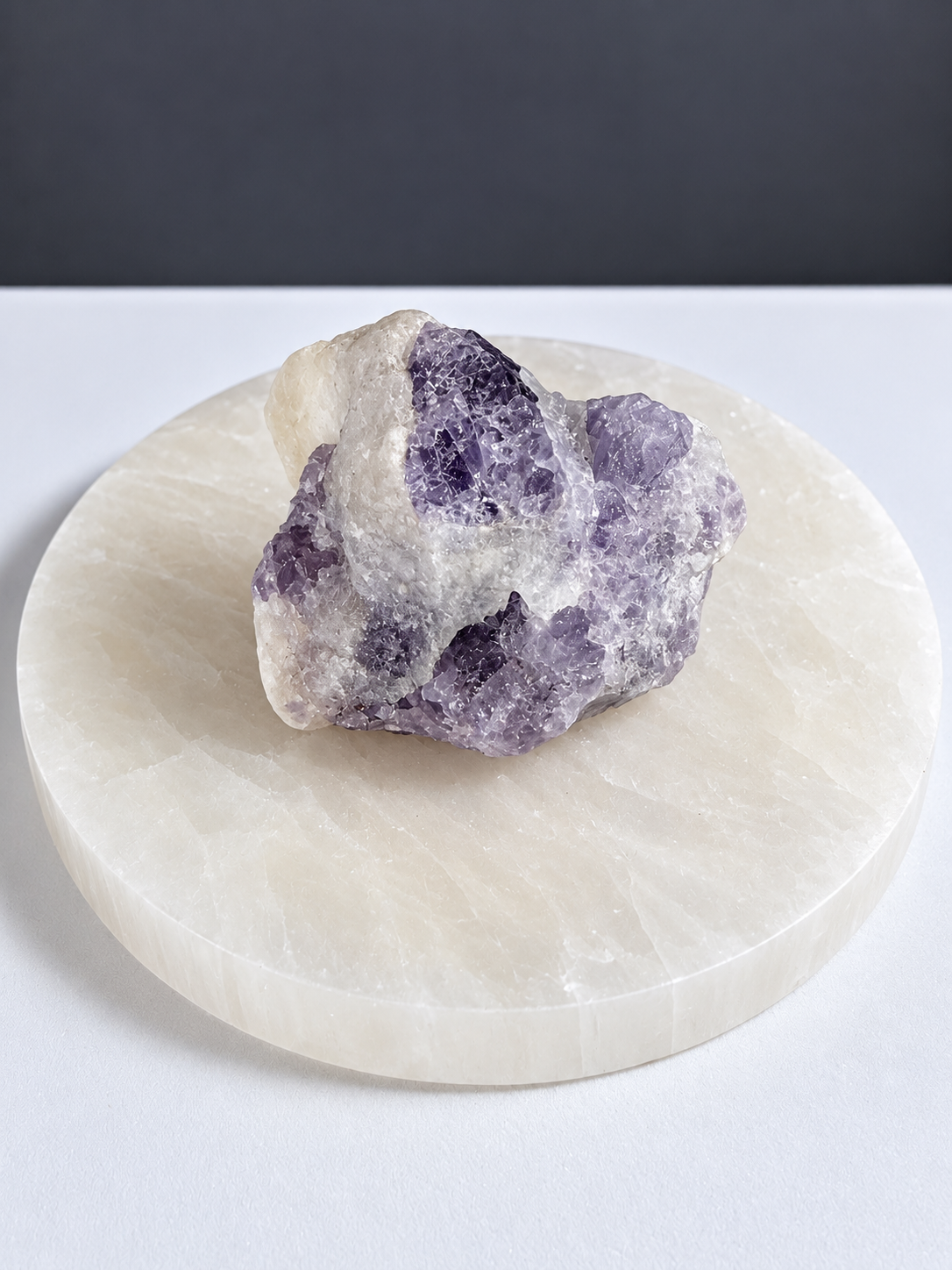 Purple scapolite natural mineral specimen on pale stone display slab