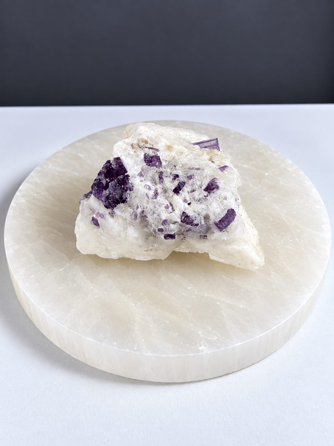 Purple scapolite crystal specimen in white matrix on pale stone display slab
