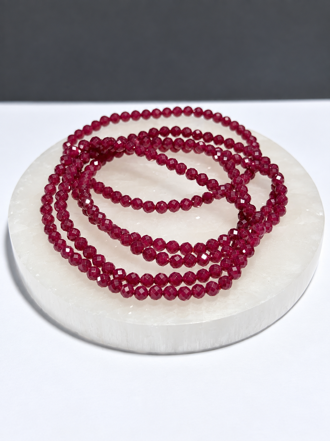 Ruby 3mm faceted stretch bracelet on white stone display