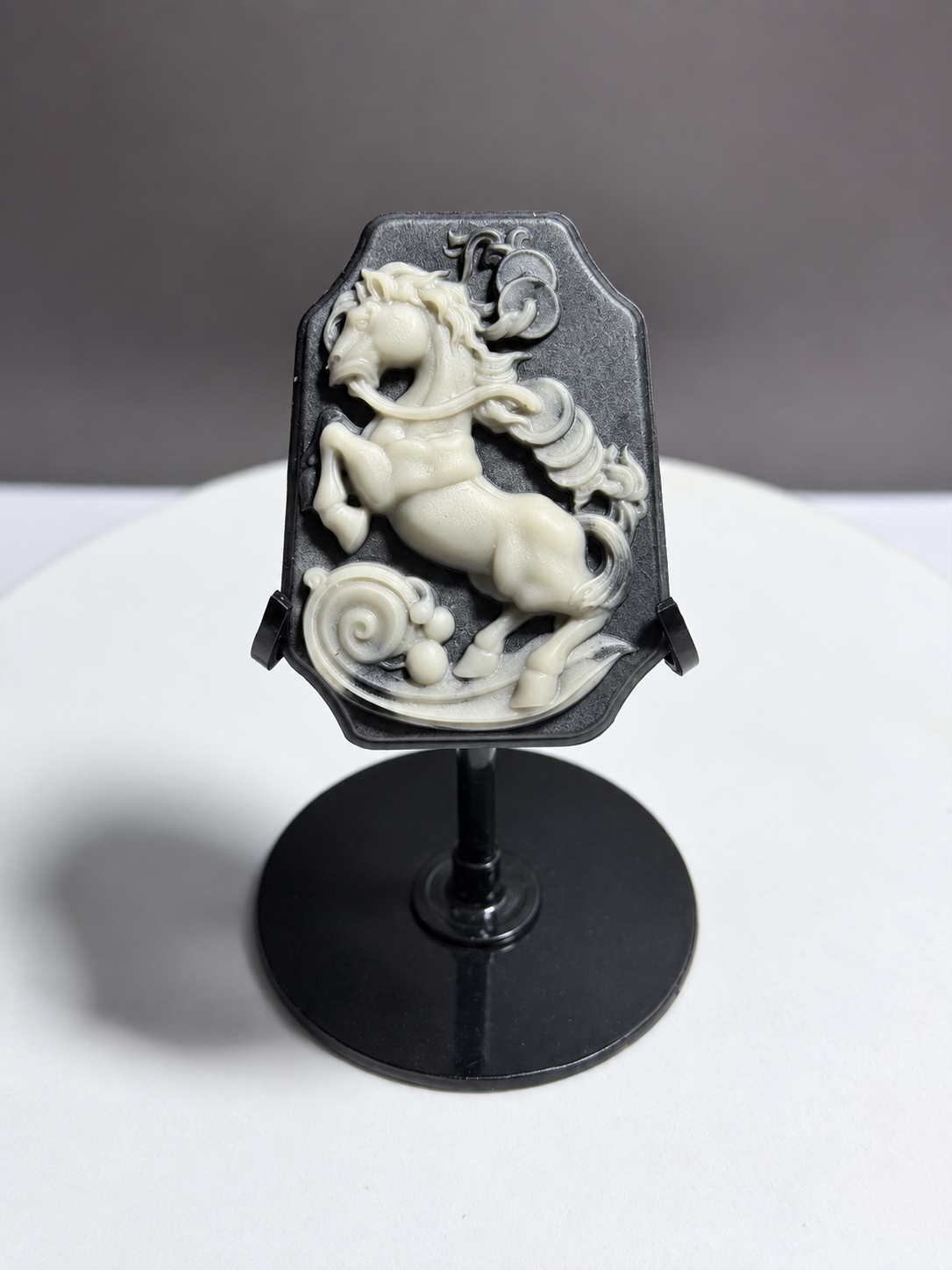 Tai Chi Stone black and cream horse relief carving displayed on black stand
